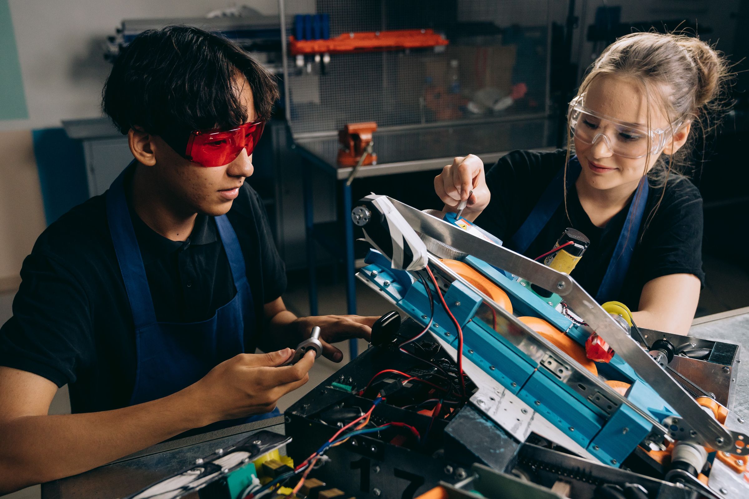 Dois alunos com EPIs montando um projeto de robótica em laboratório industrial do SENAI